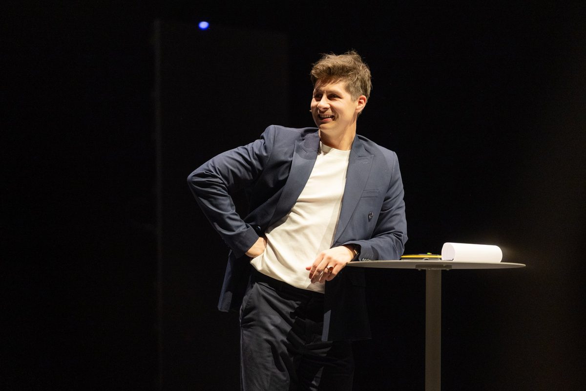 Keynote speaker Ben Hanlin on stage with his notes on the table beside him